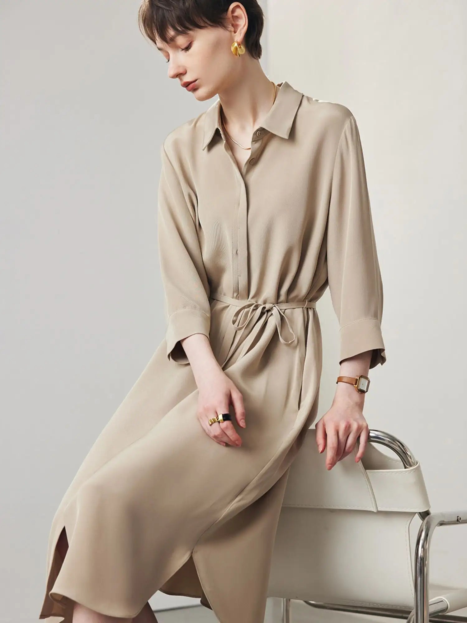 A woman wearing a tan coloured shirt dress.